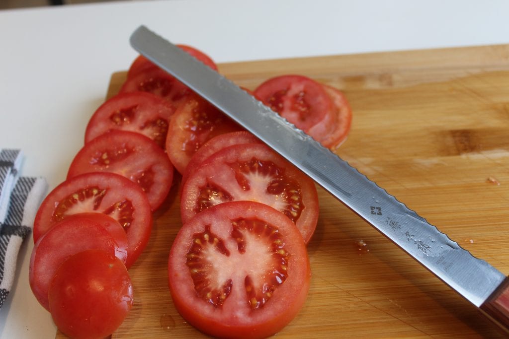 Bread knife and tomato slices on a cutting board