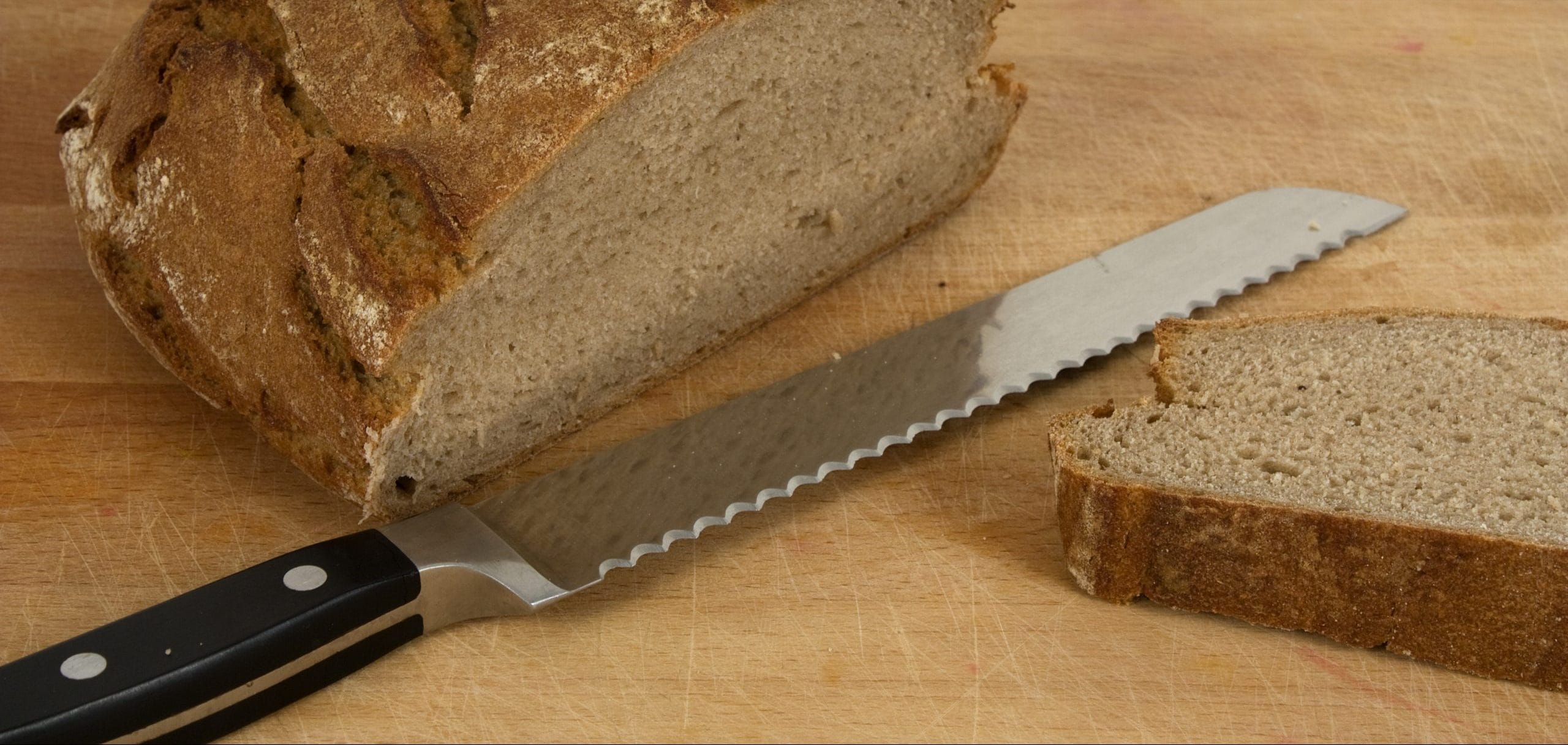 A bread knife and a bread on a cutting board