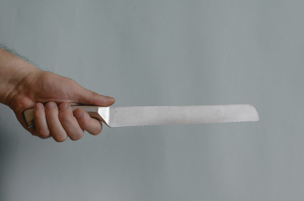 A man holds in his hand a knife for slicing bread with a metal handle