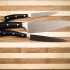 Three utility kitchen knifes on a wooden- cutting board