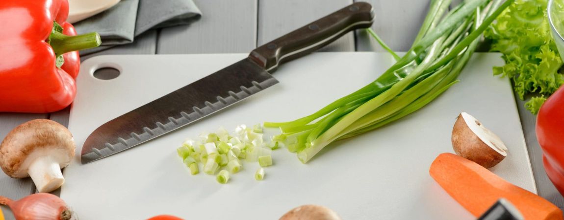 Santoku-chef-knife-and-vegetables-on-a-white-cutting-board-scaled