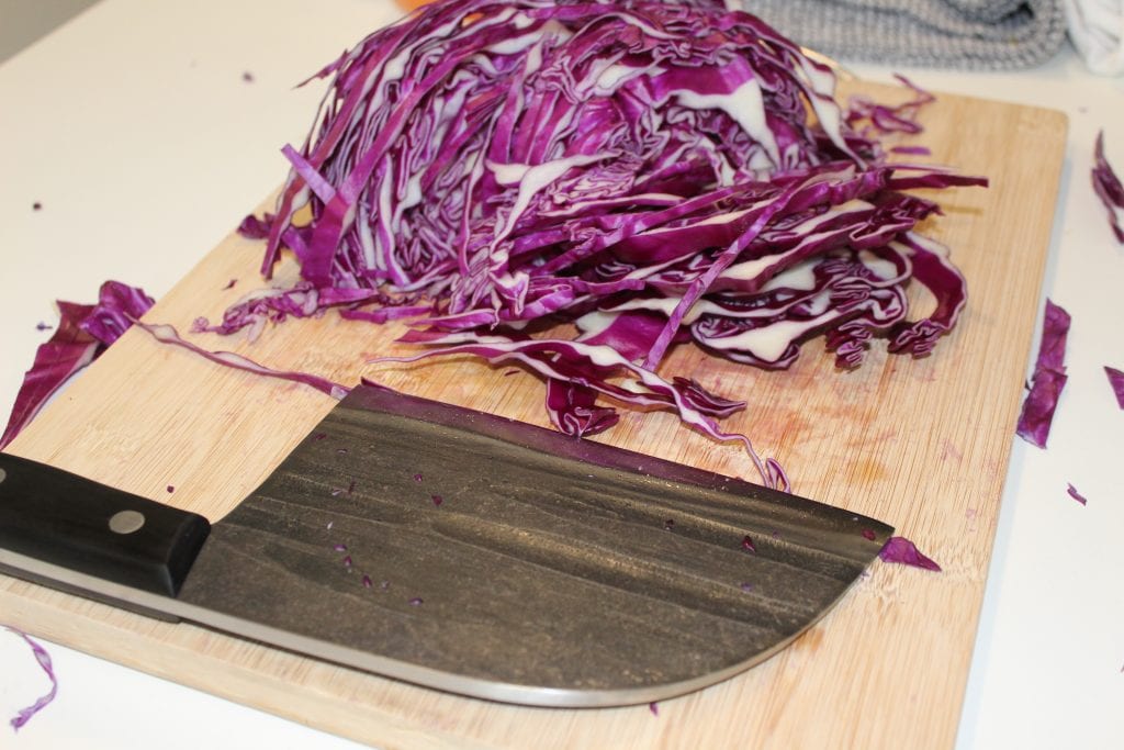 A Serbian knife on a cutting board and next to it a red cabbage cut