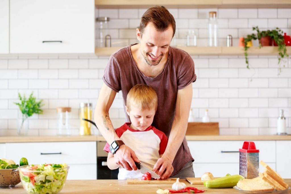 A man in the kitchen cooking with his child