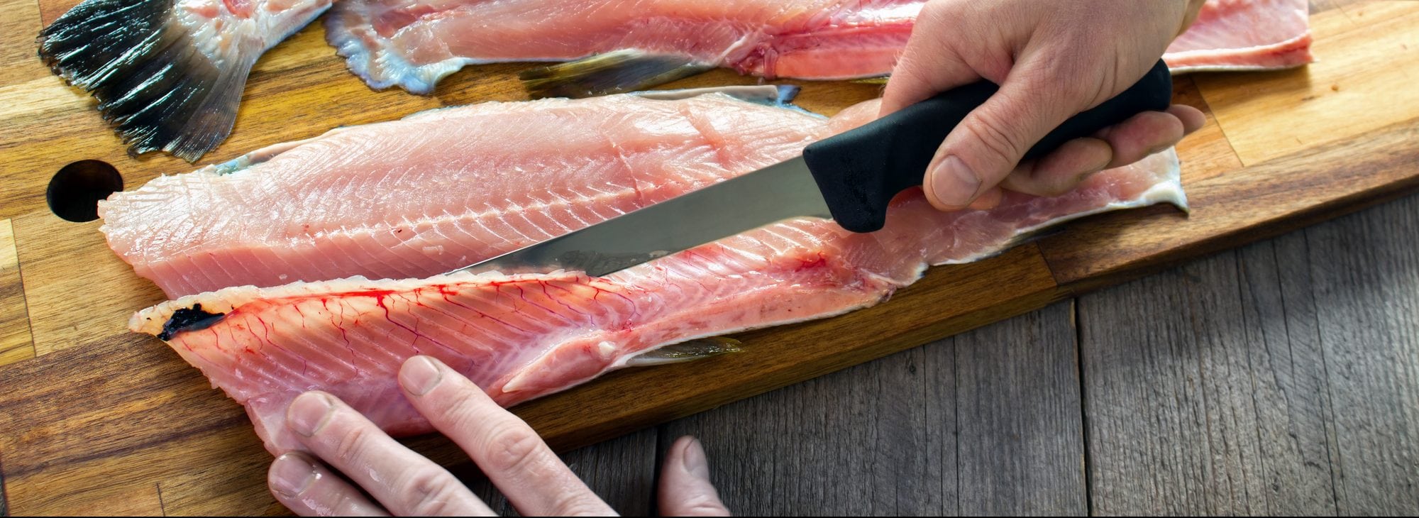 Filleting trout , removing rib bones with sharp fillet knife on wood