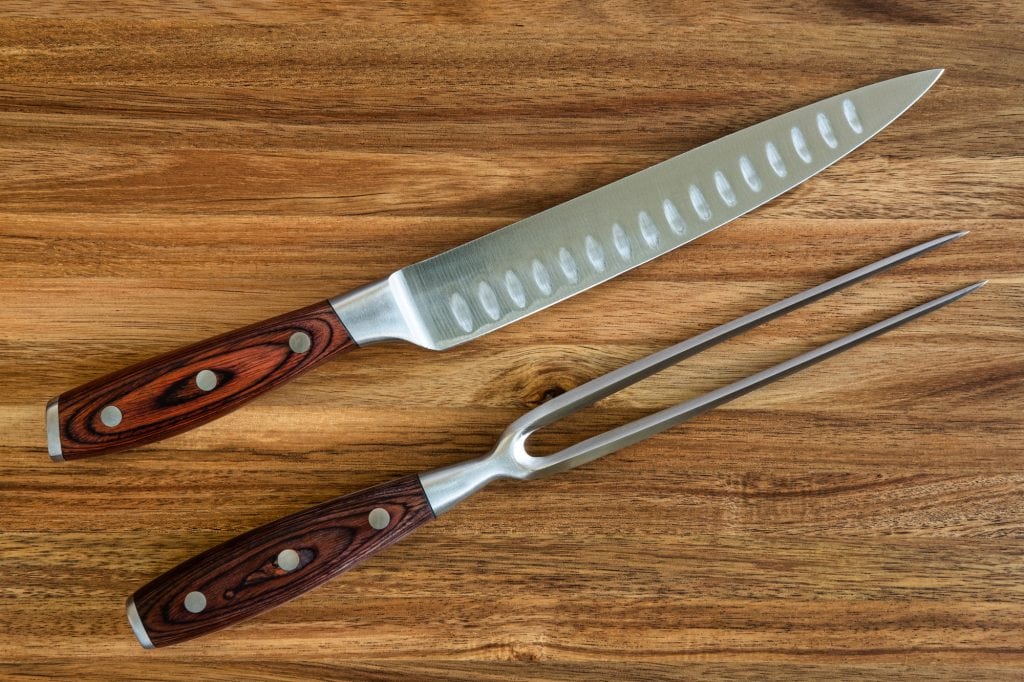 knife and fork carving set on a wood cutting board