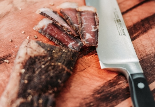 Sliced meat and a chef knife on a cutting board