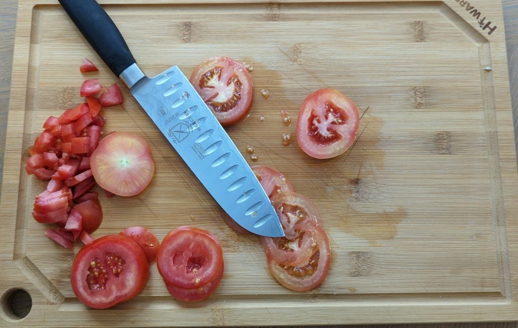 https://knivesacademy.com/wp-content/uploads/2022/06/Mercer-Genesis-Santoku-and-a-tomato-on-a-cutting-board-1024x648.jpg