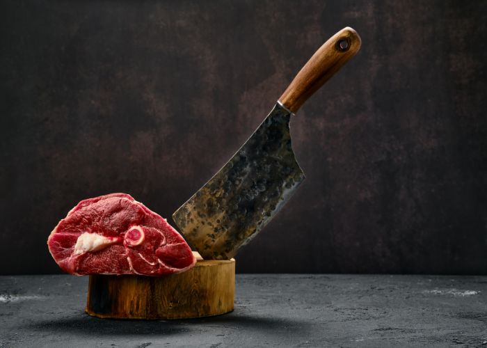 cleaver and piece of meat on wooden stand 