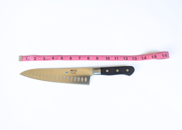 The Mac Professional 8 Inch Hollow Edge Chef Knife, horizontal on a white background while measured with a pink ruler at 12.63 inches