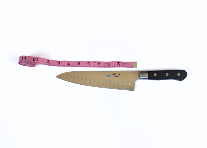 The Mac Professional 8 Inch Hollow Edge Chef Knife, horizontal on a white background while measured with a pink ruler at 12.63 inches