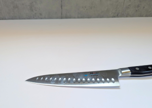 The Mac Professional 8 Inch Hollow Edge Chef Knife, horizontal on a white background with visible finger stains