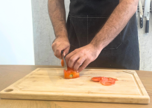 The Victorinox Fibrox Pro, held by our tester, while slicing a tomato on a cutting board