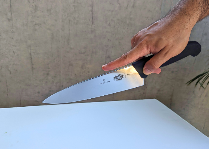 The Victorinox Fibrox Pro, held by our tester, while performing a balance test, using a finger grip on a white canvas and gray wall