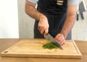 The Victorinox Fibrox Pro, held by our tester, while chopping herbs on a cutting board