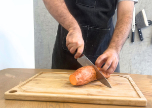 The Victorinox Fibrox Pro, held by our tester, while cutting a sweet potato on a cutting board