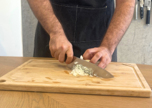 The Victorinox Fibrox Pro, held by our tester, while chopping onion on a cutting board