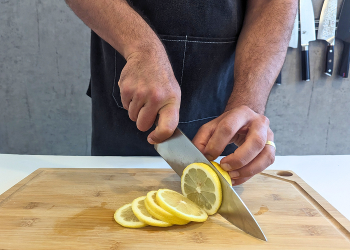 The wusthof classic 8 inch extra wide, held by our tester, while cutting a lemon on a cutting board