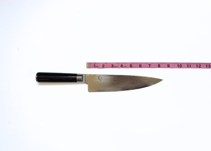 The shun knife, horizontal on a white background while measured with a pink ruler at 8