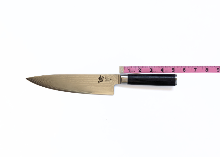 The shun knife, horizontal on a white background measured with a pink ruler at