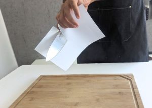 The Global, held by our tester, while execeuting a paper test on a cutting board