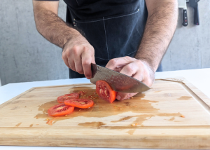 The Dalstrong, held by our tester, while execeuting a soft tomato test on a cutting board
