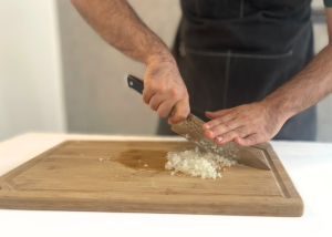 The Dalstrong, held by our tester, while chopping onion on a cutting board