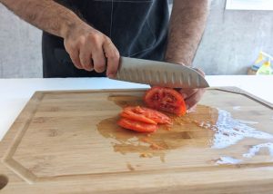 The Mercer, held by our tester, while execeuting a soft tomato test on a cutting board