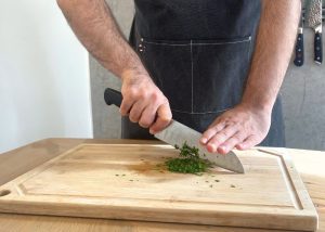 The Mercer, held by our tester, while chopping herbs on a cutting board