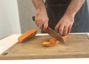 The Mercer, held by our tester, while cutting a sweet potato on a cutting board