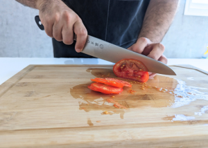 The Tojiro Fujitora DP, held by our tester, while execeuting a soft tomato test on a cutting board